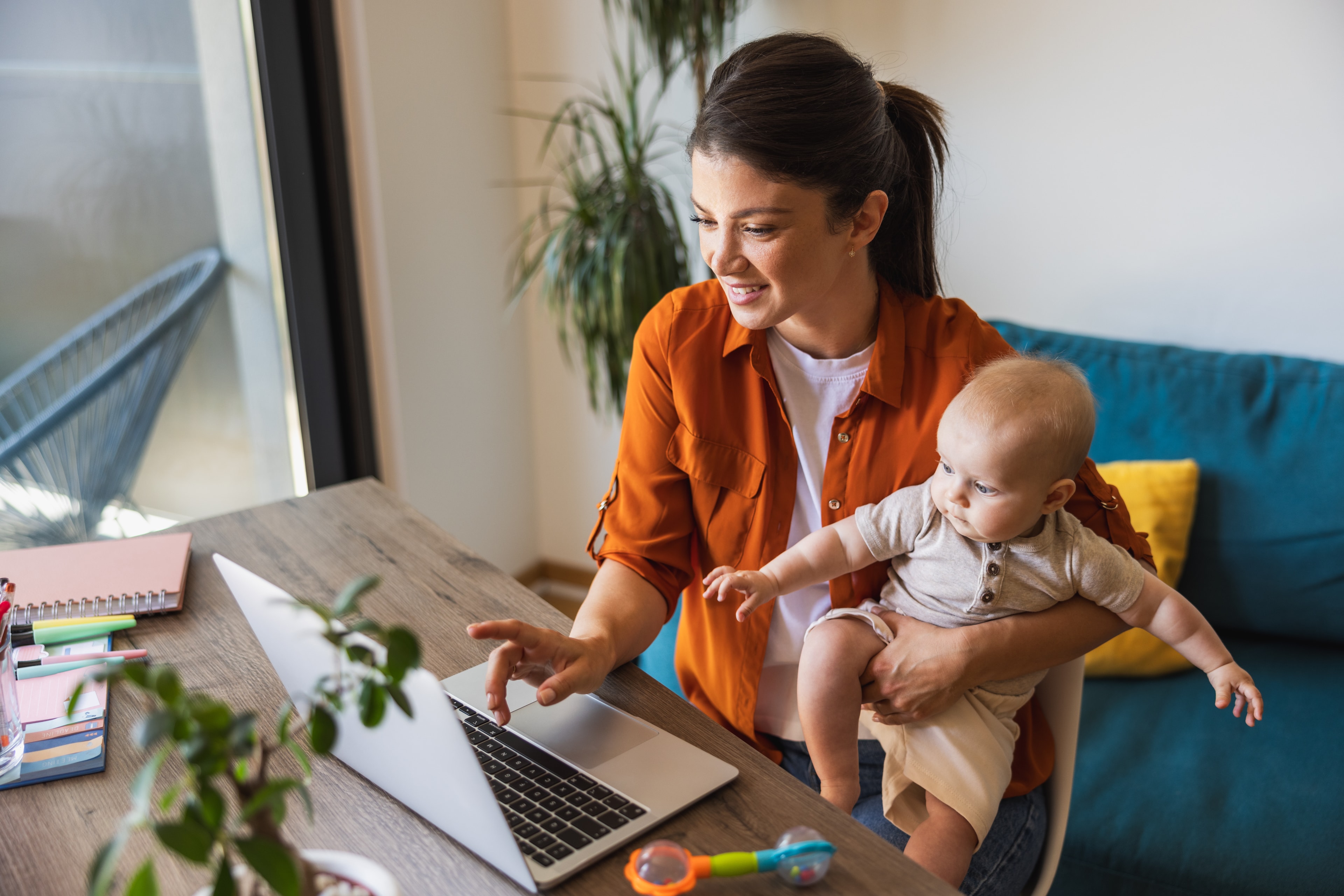 Mutter mit Baby arbeitet am Laptop — Vereinbarkeit von Familie und Beruf